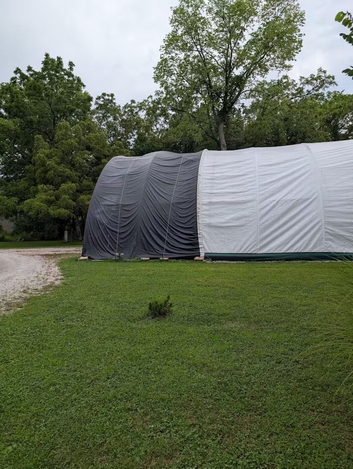 Upcycled black vinyl tarp used as a waterproof boat cover for outdoor storage